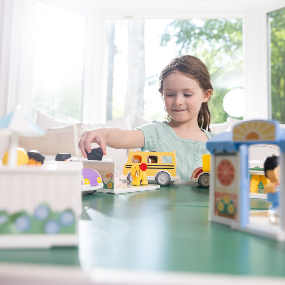Child playing with Melissa & Doug Cheery Lane houses, vehicles and figures